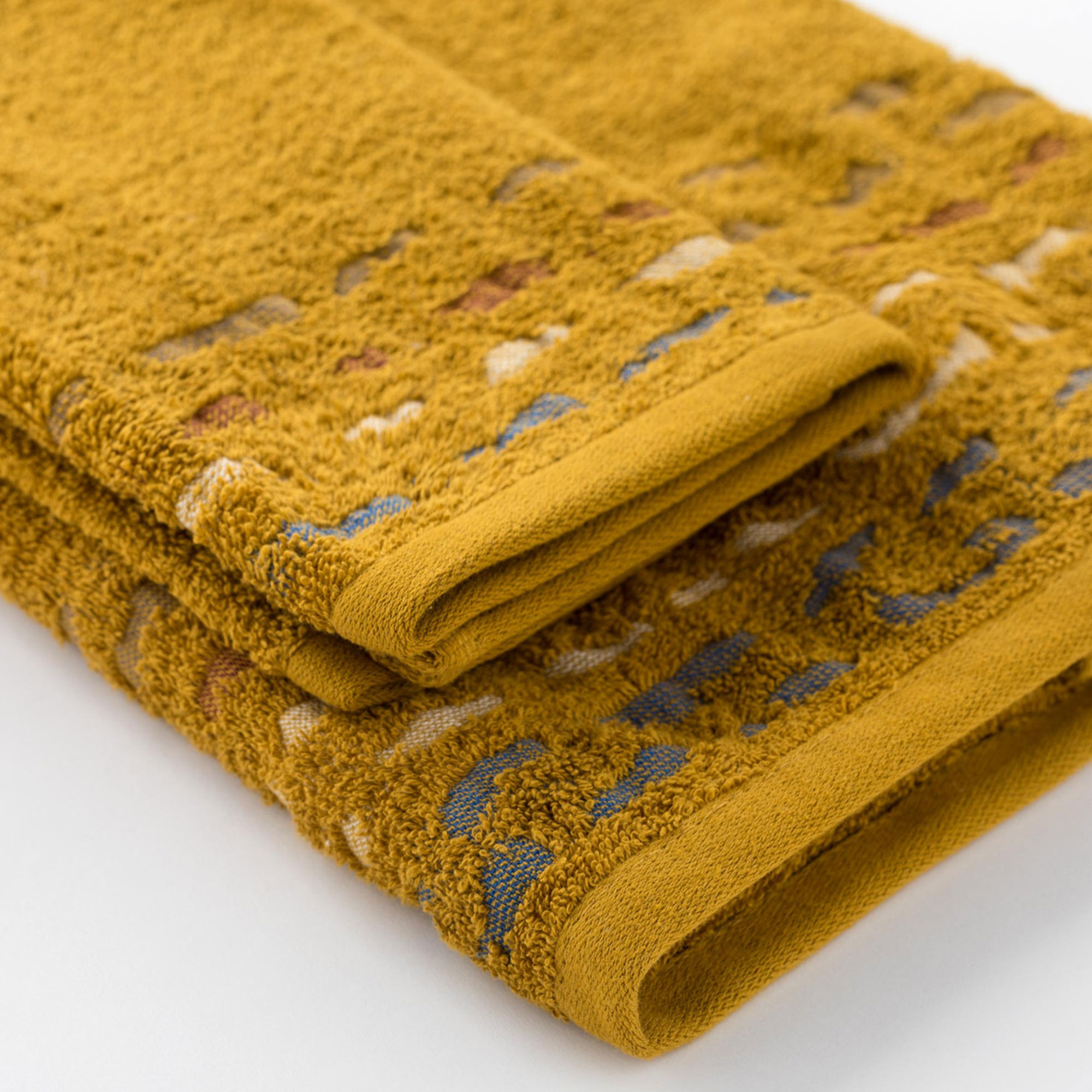 dettaglio-asciugamano-con-ospite-gatsby-ocra dettaglio asciugamano con ospite Gatsby di Riviera in spugna jacquard ocra